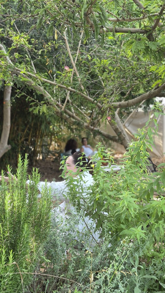 אישה בפינת גינה ירוקה ופורחת